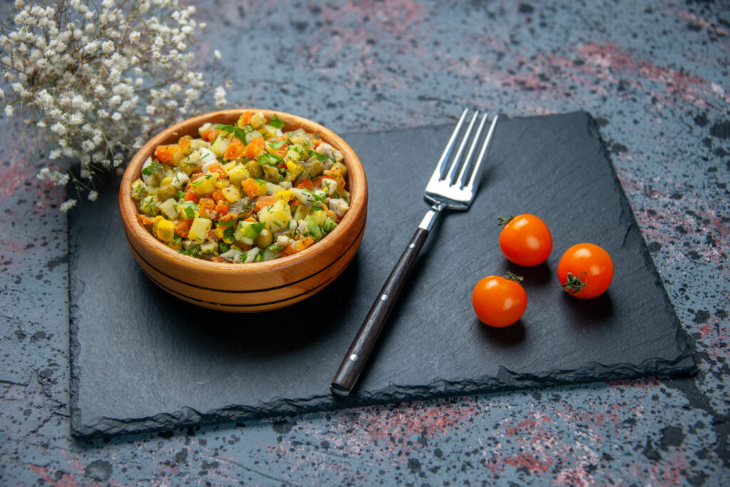 Home front view boiled vegetable salad with fork blue background