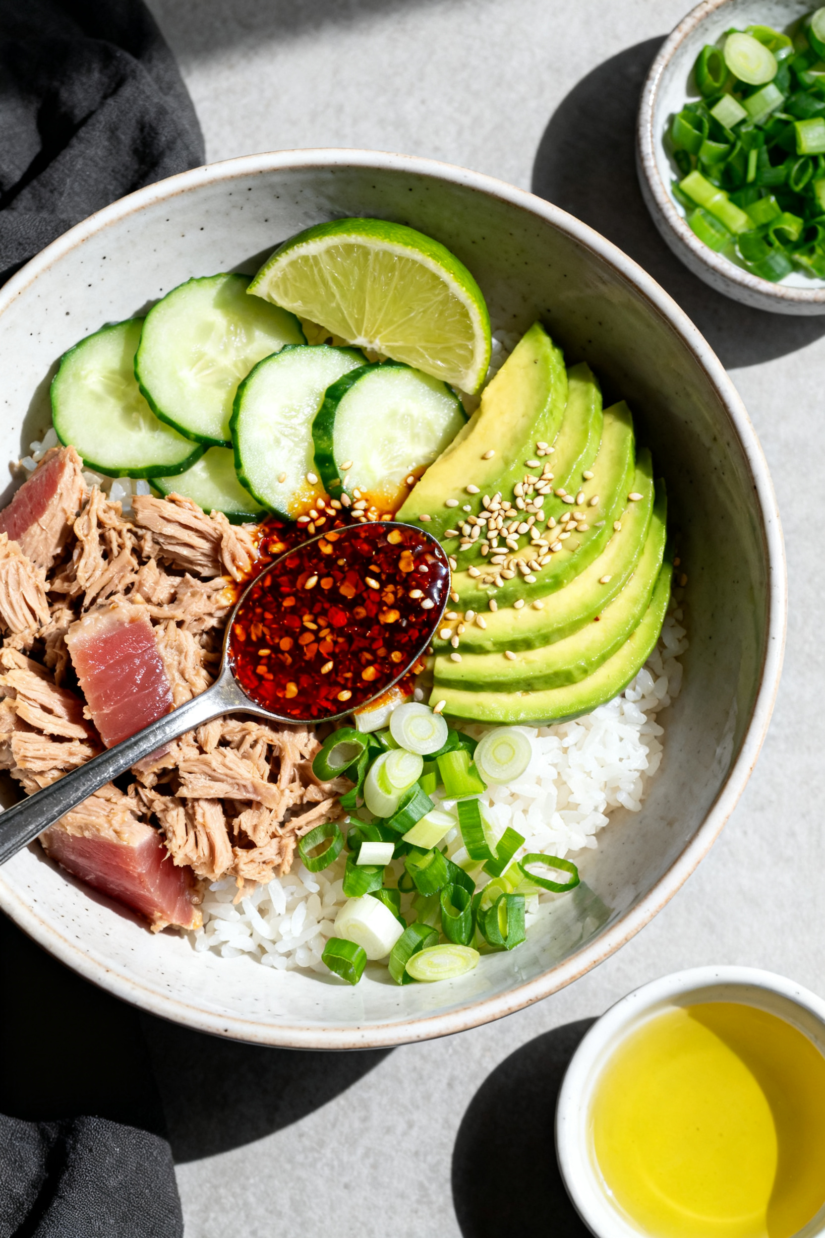 Tasty top view: Overhead shot of a Chili Crisp Tuna Bowl—steaming warm white rice base topped with