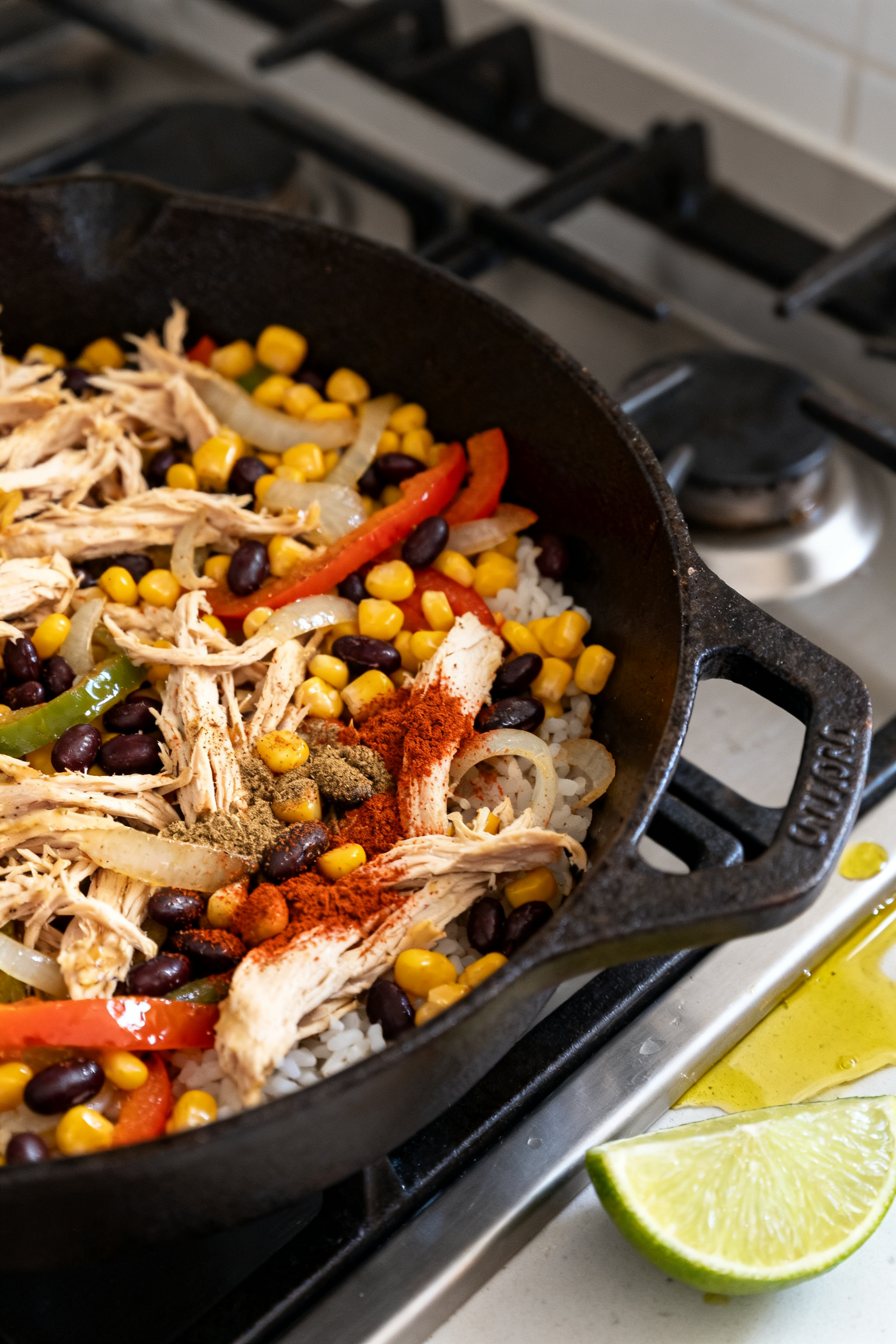 Cooking process: Southwest Chicken Rice Bowl components sizzling in a cast-iron skillet—shredded l
