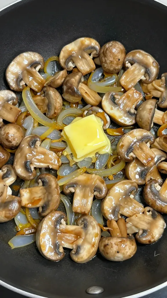 Sautéed mushrooms and onions in skillet, butter glistening