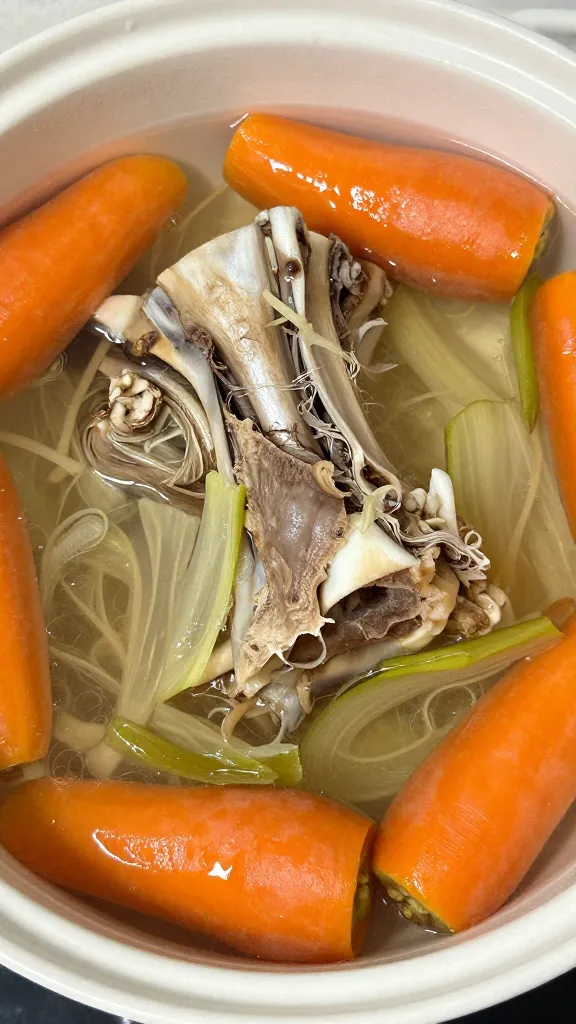 ham bone simmering with carrots and celery in pot