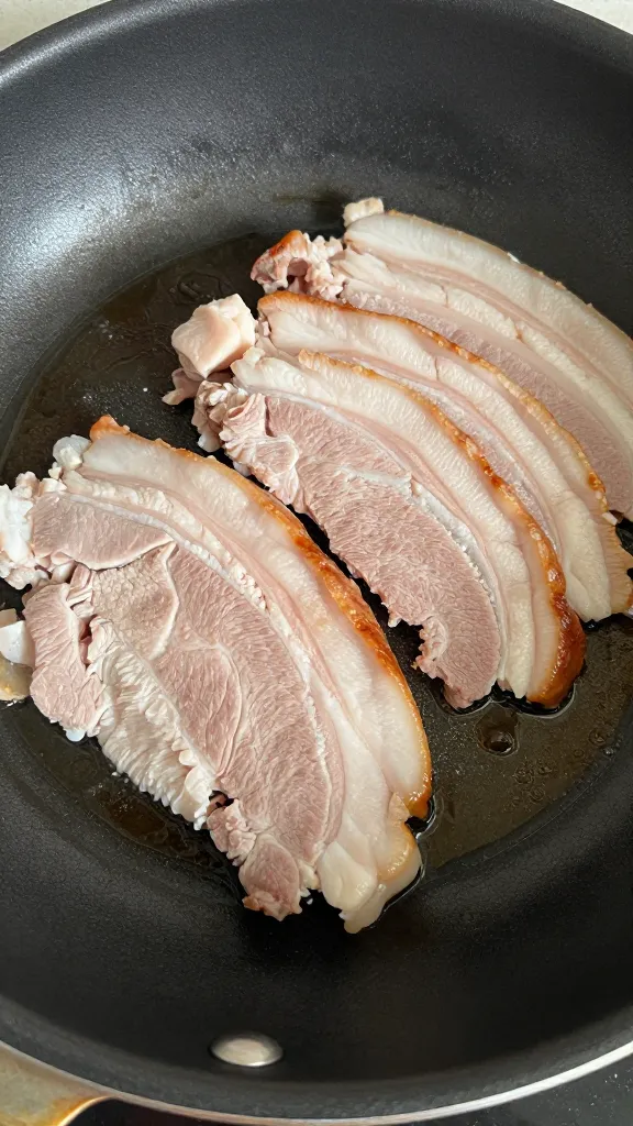 Thin-sliced leftover pork roast in hot skillet, searing